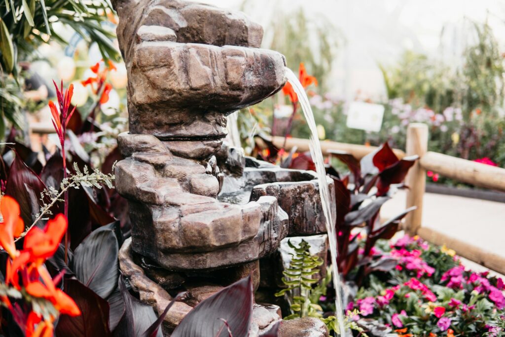 a water fountain in a garden filled with flowers
